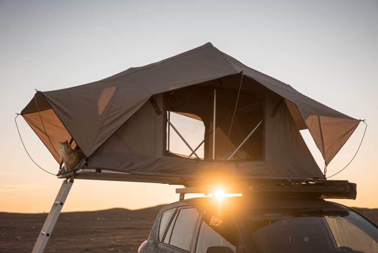 Tente de toit de voiture pour le camping sur le toit d'une voiture tout-terrain dans le désert au coucher du soleil