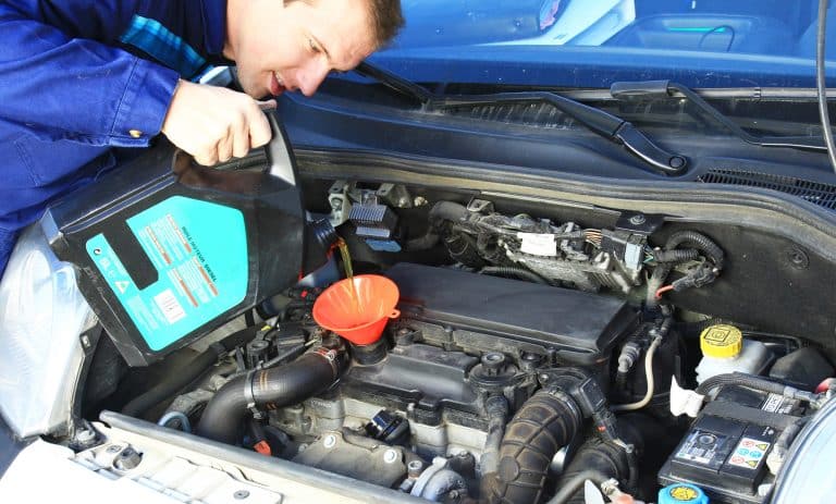 huiles moteur 5W30 et 5W40 en remplissage sous le capot moteur d'une voiture par un mécanicien