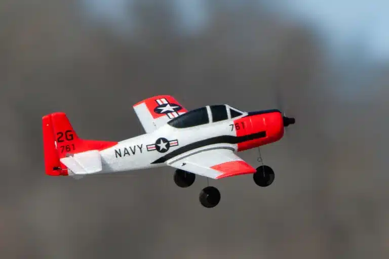 avion radio commandé rouge et blanc dans les airs avec le fond flouté